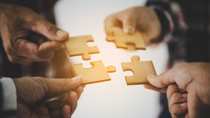 Hands holding piece of blank jigsaw puzzle for teamwork
