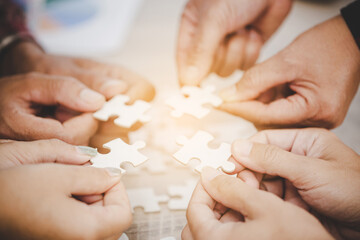 Hands holding piece of blank jigsaw puzzle for teamwork