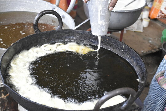 Indian male hand making Indian popular sweet dish Jalebi. Jalebi, also known as jilapi, jilebi, jilipi, zulbia, jerry, mushabak, or zalabia, is a popular Indian sweet snack.