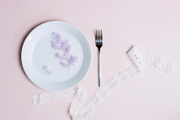 Diet concept with empty plate and fork over the pink background. 