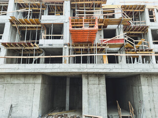 Low angle shot of a construction site with half-build structure. Process of building concrete apartment house. Concept of investing and mortgaging in the stage of home building