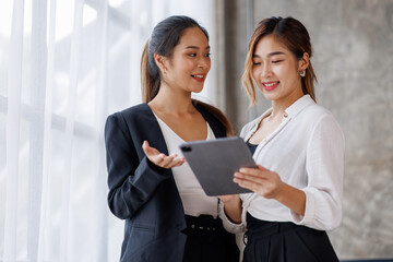 Businesswoman executive is using a tablet in meeting discussion with another businesswoman or client in modern workplace office. People corporate Asian business people team concept.
