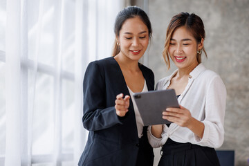 Obraz premium Businesswoman executive is using a tablet in meeting discussion with another businesswoman or client in modern workplace office. People corporate Asian business people team concept.