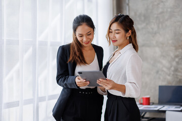 Obraz premium Businesswoman executive is using a tablet in meeting discussion with another businesswoman or client in modern workplace office. People corporate Asian business people team concept.