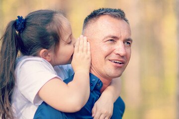 Little girl whispering in father ear