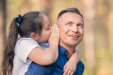 Little girl whispering in father ear
