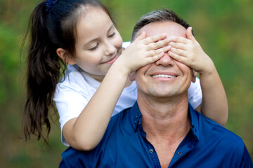 Little girl covering eyes of her father