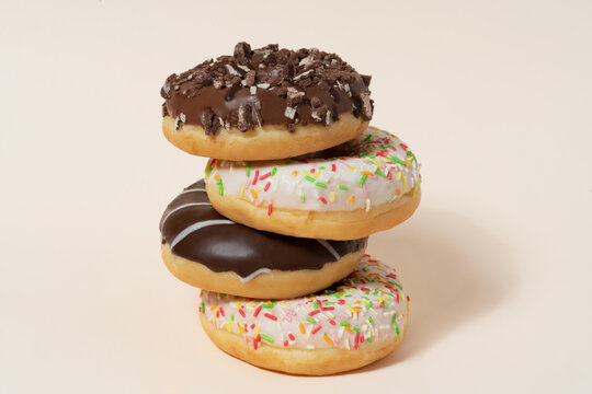 Colorful glazed donuts arranged verticaly on the beige background