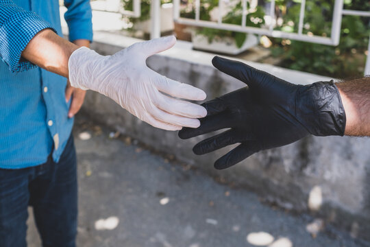 gloved handshake. Wearing gloves to avoid monkeypox and diseases. gloved hands hold.