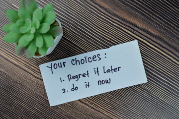 Naklejka premium Concept of your choices - regret it later or do it now write on sticky notes isolated on Wooden Table.