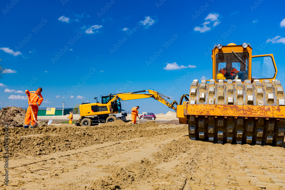 Wall mural road roller with spikes and earthmovers are working at construction site