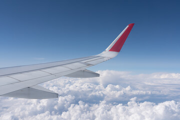 Blick auf weiße Wolken am Himmel aus dem Fenster eines Flugzeugs über der Tragfläche
