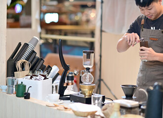 Closeup of Asian Male Barista using a coffee machine in a coffee shop to make coffee for customers to order inside a coffee shop cafe in Thailand.