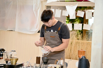Closeup of Asian Male Barista using a coffee machine in a coffee shop to make coffee for customers to order inside a coffee shop cafe in Thailand.