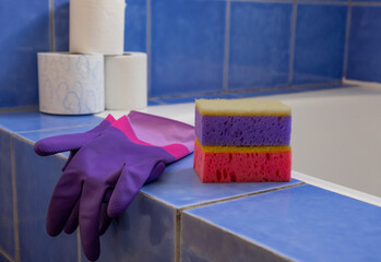 Rubber gloves and sponges inside bathroom. Closeup. Set of colorful accessory for house cleaning