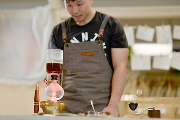 Closeup of Asian Male Barista using a coffee machine in a coffee shop to make coffee for customers to order inside a coffee shop cafe in Thailand.