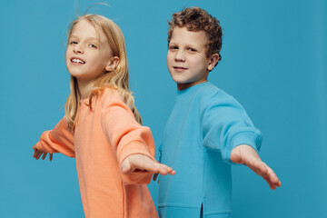 cute, beautiful children are standing on a blue background with an empty space for an advertising...