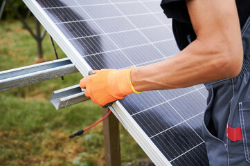Close up of man engineer installing solar modules. Male worker in work gloves mounting solar...