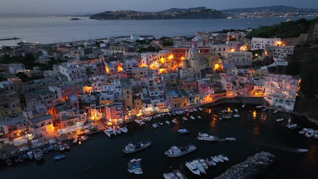 night view of Procida old town and harbor in the bay of Napoli in Italy. Aerial view of southern Italian fishing village in the evening near Naples, island of Procida at night