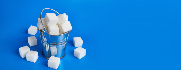 A small bucket with cubes of pressed sugar on a blue background.
