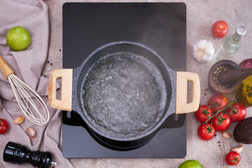 Boiling water in a cooking pot an a pan on a induction stove at domestic kitchen