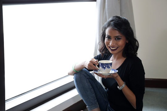 Asian female dark skinned Indian Bengali subcontinent at home office table chair business work study look smile emotion confident sit on the floor drink tea cup