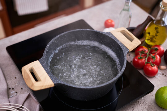 Boiling water in a cooking pot an a pan on a induction stove at domestic kitchen