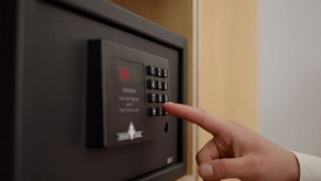 man hand in white shirt enters password on bank safe. Businessman keeps his savings and documents in strongbox, close view of entering digital code on an electronic scoreboard.