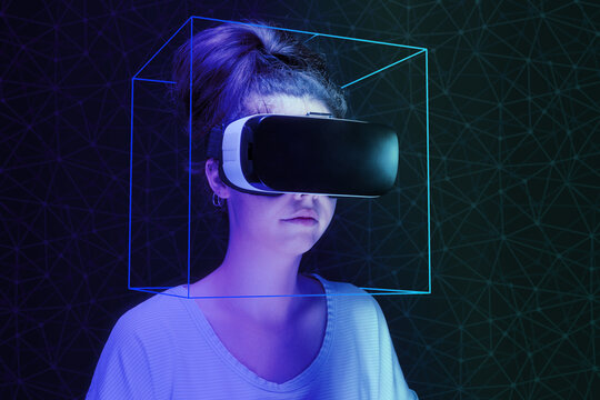 Metaverse and 3D simulation. A young woman in VR glasses and neon laser cube helmet. Dark background with neon mesh. The concept of virtual reality and cyberspace