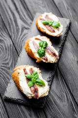 sandwich with anchovy fillet on a tray for serving on a black wooden rustic background