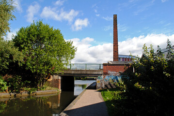 Canal and Towpath with Bridge and Industrial Chimney seen against  Blue Sky 