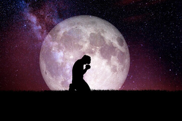 A desperate and lonely man knelt down and prayed to God. There is a moon in the background at night. Desperate, heartbreaking, and lonely concepts