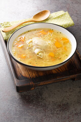 Light chicken soup with pasta and vegetables close-up in a bowl on a wooden tray on the table. Vertical © FomaA