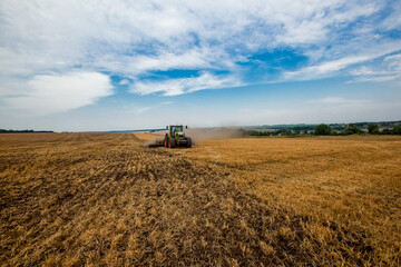 Tractor working in wheat field. Agriculture background. Harvest season