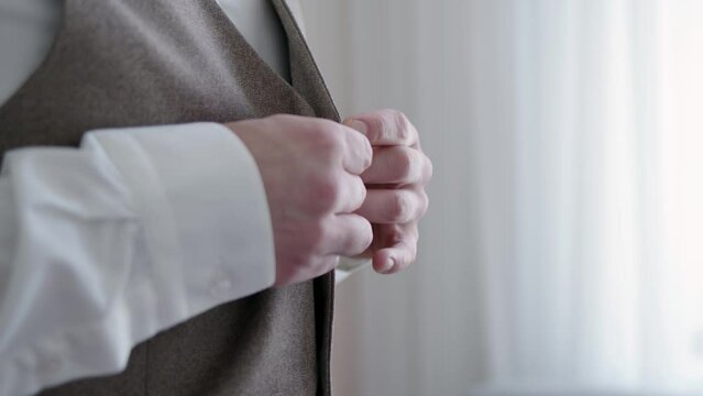 businessman has returned from meeting and unbuttoning buttons on his suit vest. man takes off his clothes and prepares to take break from hard day after meeting with customers or suppliers.