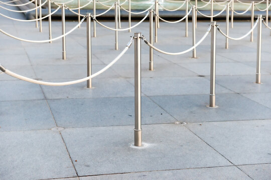 Path with line of silver metal poles in front of ticket office with no people