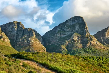 Cercles muraux Montagne de la Table Paysage d& 39 une montagne à Cape Town, Afrique du Sud dans la journée. Sommet rocheux avec verdure contre ciel nuageux. Ci-dessous une attraction touristique populaire et un sentier de randonnée d& 39 aventure près de la montagne de la table