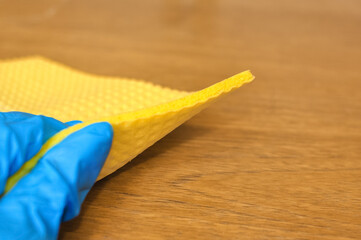 Hand with yellow rag a wooden background