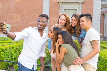Multiethnic group of friends taking a selfie with mobile outdoors