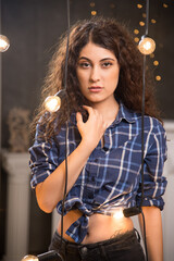 Portrait of a young model in plaid shirt posing near lamps