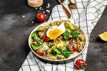 Quinoa buddha bowl with avocado, egg, tomatoes, spinach and sunflower seeds on a dark background. Homemade food. Healthy, clean eating. Vegan or gluten free diet, place for text, top view