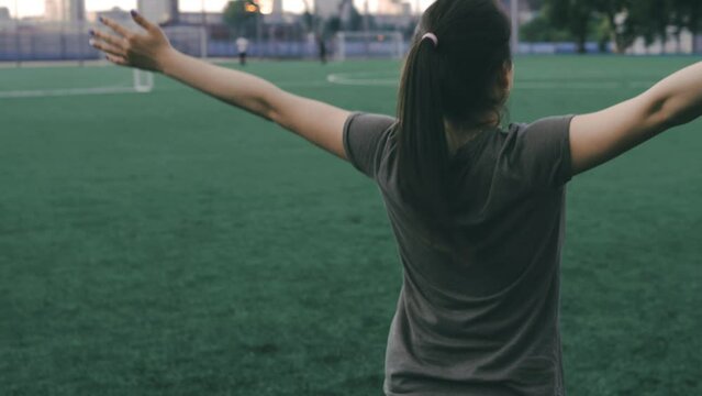 Portrait of a happy female football player with raised hands standing at the stadium. Dreams come true. Professional female player, soccer star