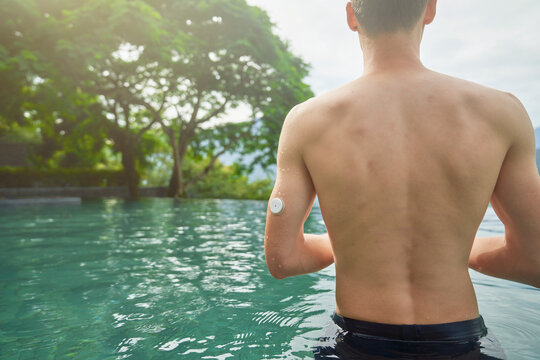 Diabetes patient in a swimmingpool with an waterproof CGM (Continuous Glucose Monitor) device to measure real-time blood sugar for a healthy lifestyle without setbacks for a good healthcare.