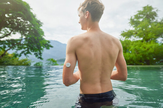 Diabetes patient in a swimmingpool with an waterproof CGM (Continuous Glucose Monitor) device to measure real-time blood sugar for a healthy lifestyle without setbacks for a good healthcare.
