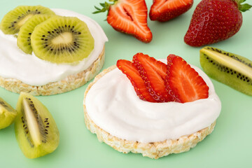 Rice crispbread with sliced strawberry and kiwi. Crispy snack with cream cheese and fruit for...
