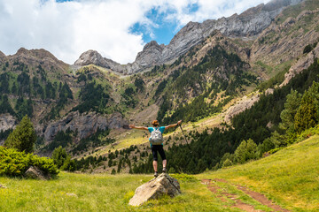 A young woman with open arms in the mountains in summer in the Pyrenees, Alto Gallego, Huesca, Aragon