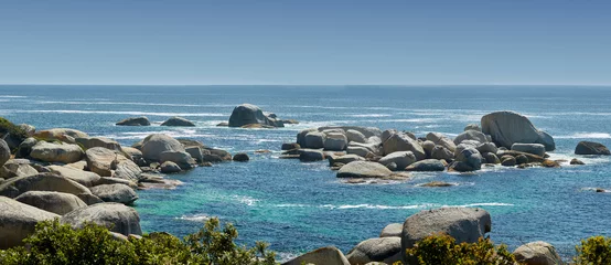 Fototapeten Landscape of large rocks in the ocean in summer. Many stones by the wide, empty seaside. Smooth rocks or cliffs by the beach with light foamy waves at the surface, Hout Bay, Cape Town, South Africa © SteenoWac/peopleimages.com