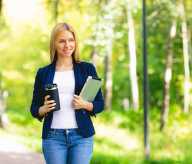 Fototapeta premium Young smiling beautiful woman in park with tablet gadget and wireless headphones enjoying - green energy concept, remote work