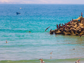 Agadir, Morocco - 14 AUGUST 2020 : People swimming in the edge of a harbor, in the blue atlantic...