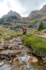 Fototapeta na wymiar Woman with her son in the backpack walking in the Pyrenees in summer, Valle de Tena, Huesca